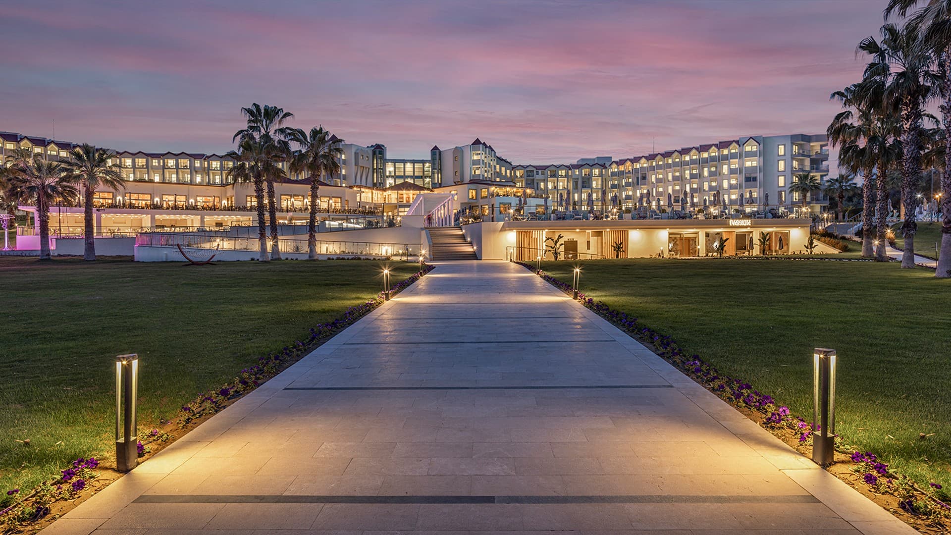 Lit pathway leading to the hotel at sunset